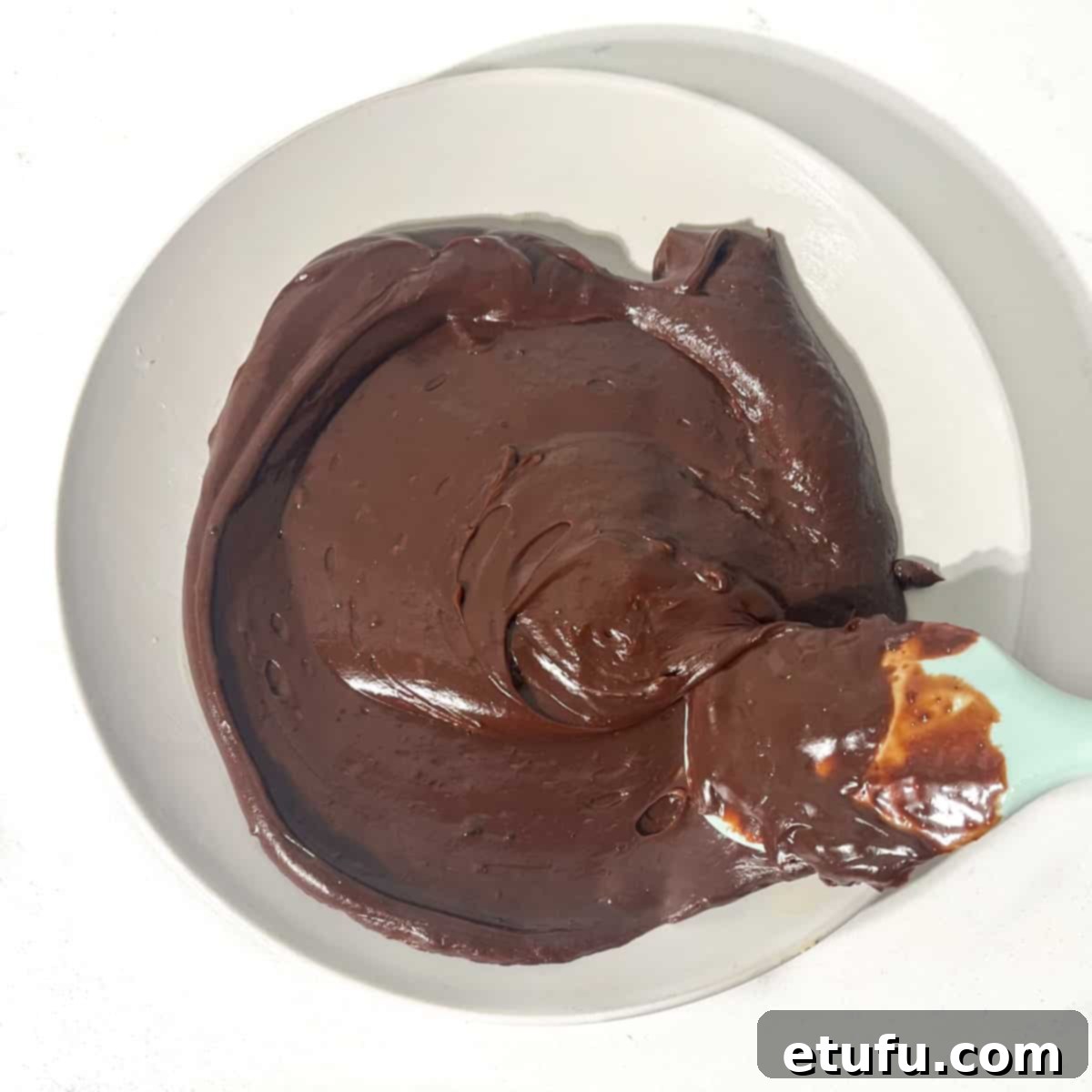 The brigadeiro mixture being spread out on a buttered plate with a spatula.