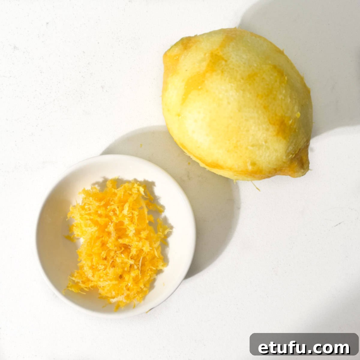 A zested lemon and a small bowl with lemon zest.