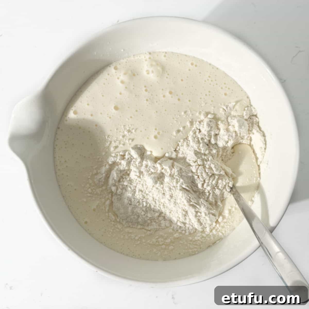 Adding half the flour to the egg and sugar mixture.