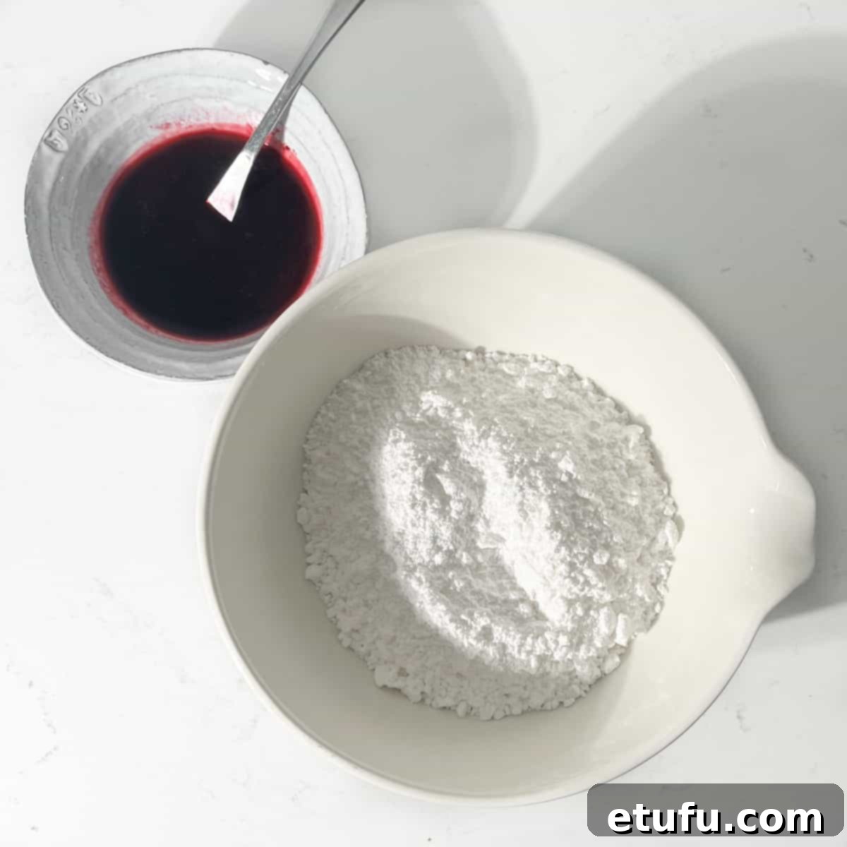 A bowl of blueberry juice and a bowl of icing sugar.