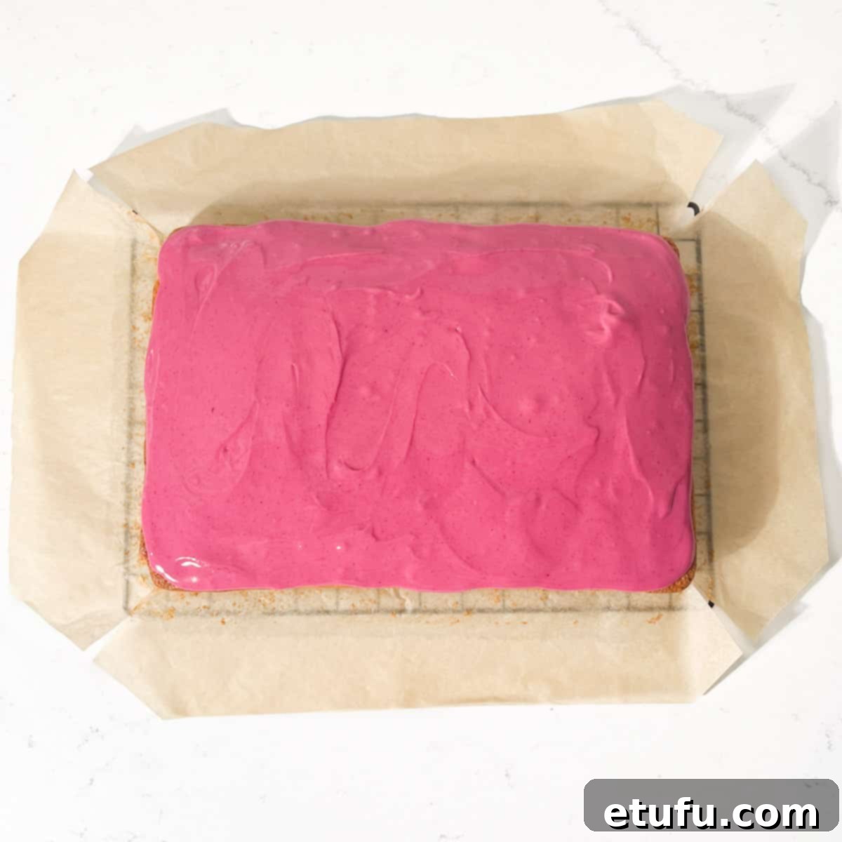 An iced Tottenham cake on a black wire cooling rack.