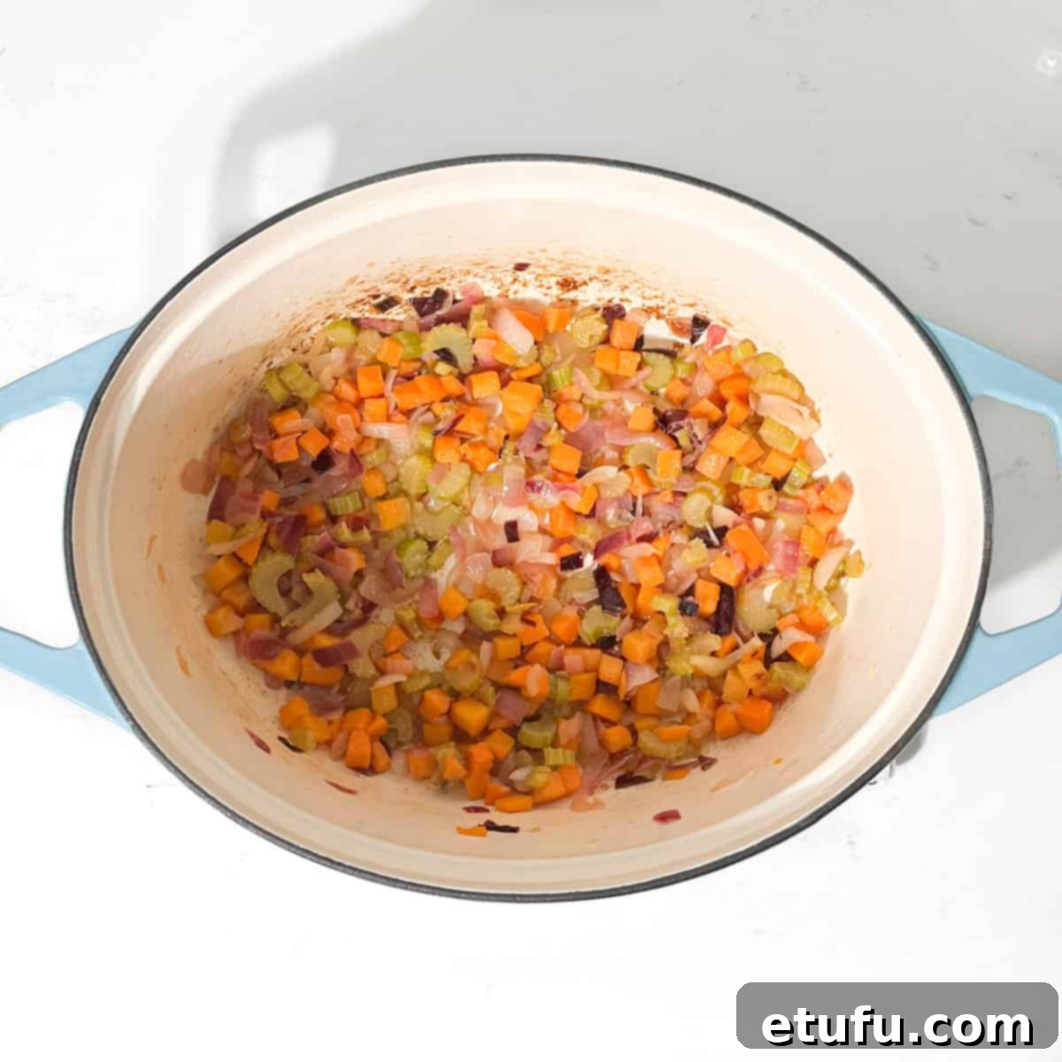 Vegetables in a large pot stir fried until soft and lightly coloured.