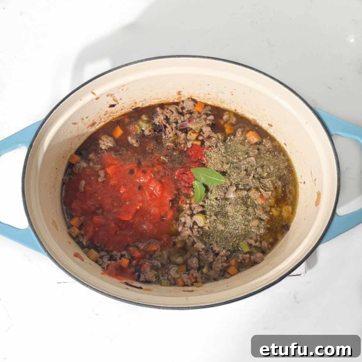 Adding tomatoes and herbs to the pot for the mince and dumplings.