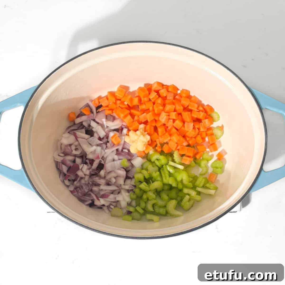 Adding all the vegetables for the mince and dumplings to a large pot.