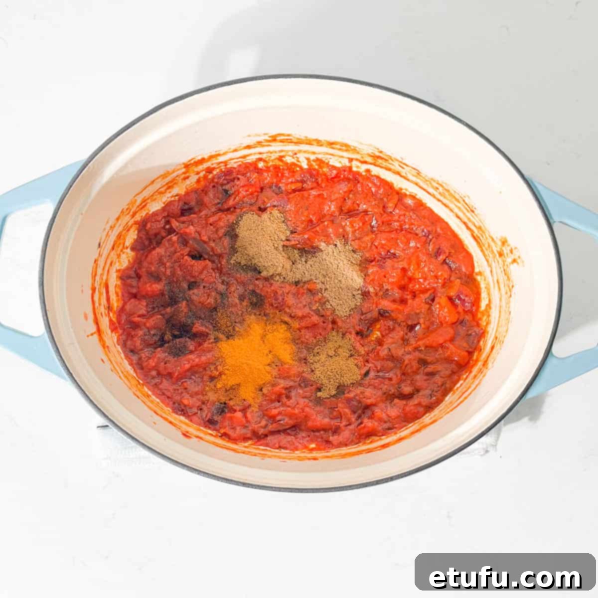 Adding all the spices for the Chicken Handi to the tomato base in a large pot.