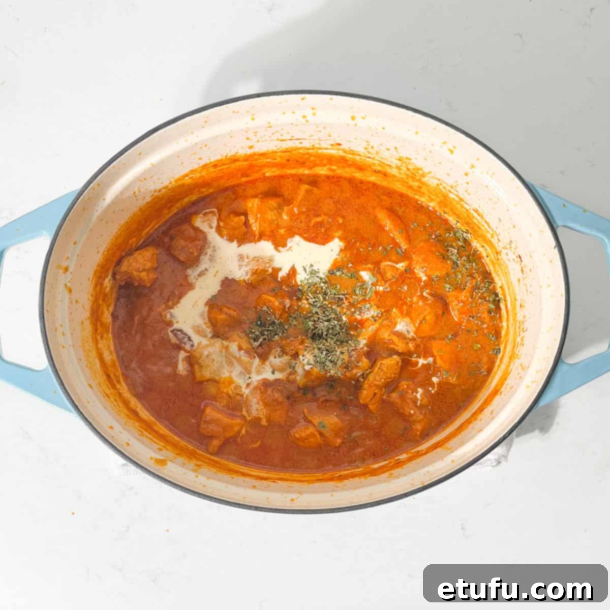 Adding yoghurt to the Chicken Handi in a large pot.