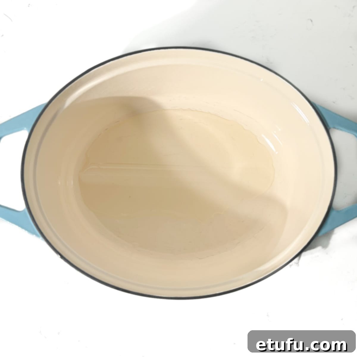 Adding oil to a large oval pot to heat up. 