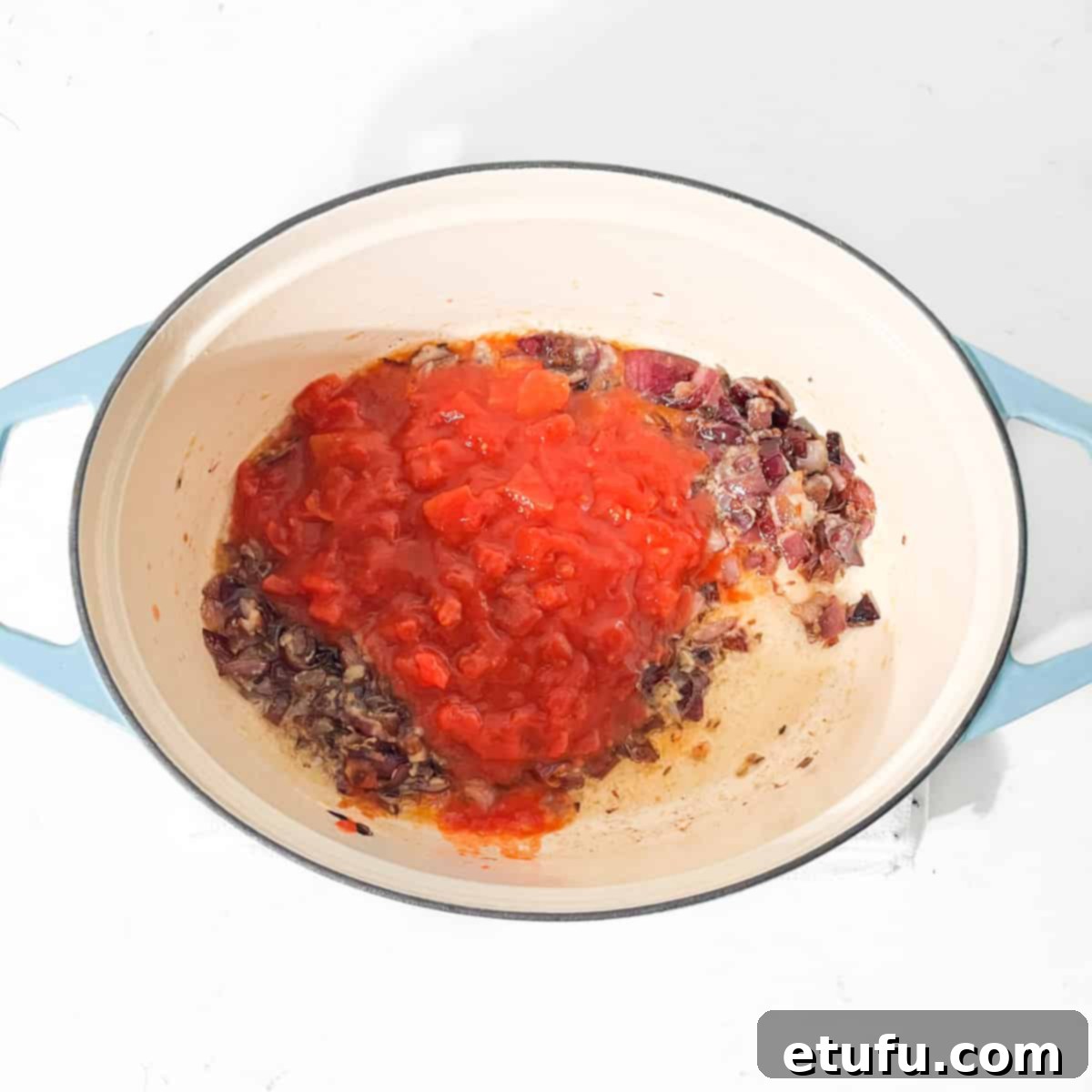 Adding chopped tomatoes to fried onions for the chicken curry.