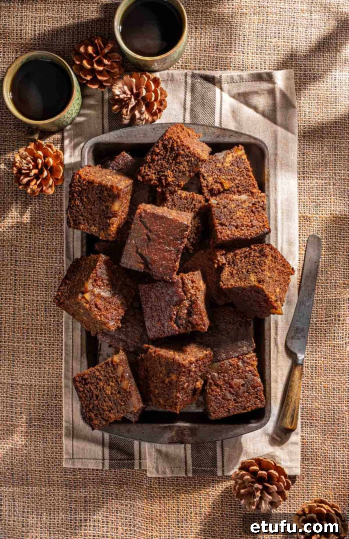 Squares of Jamaican ginger cake in a baking tin on a hessian background. 
