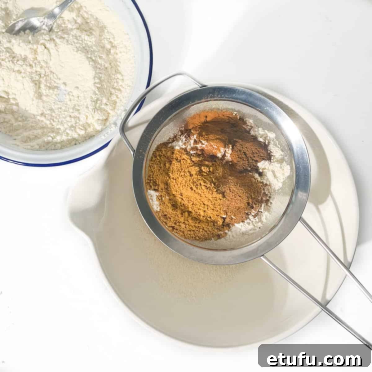 Sifting flour and spices into a large white mixing bowl.