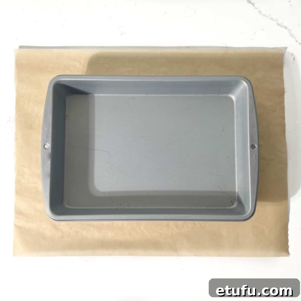 A baking tin on a rectangular piece of baking paper.