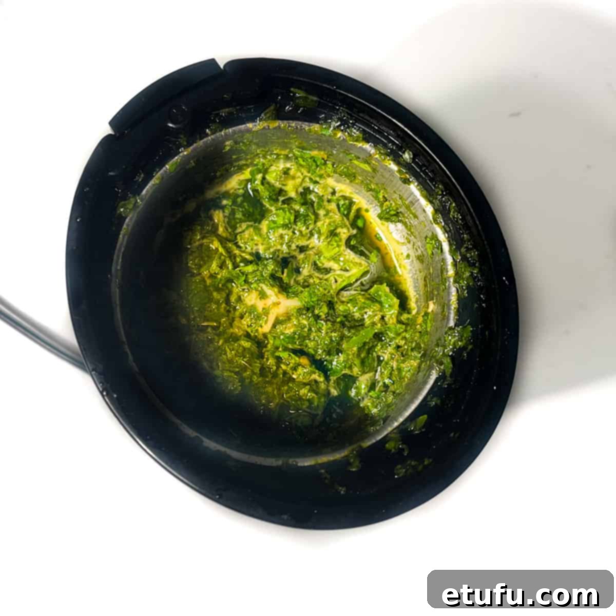 Mint, coriander, and water being added to a small blender, the initial step for making mint sauce.