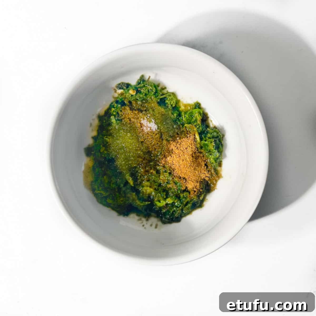 All the blended ingredients and spices being added to a bowl of yogurt for the Indian mint sauce.