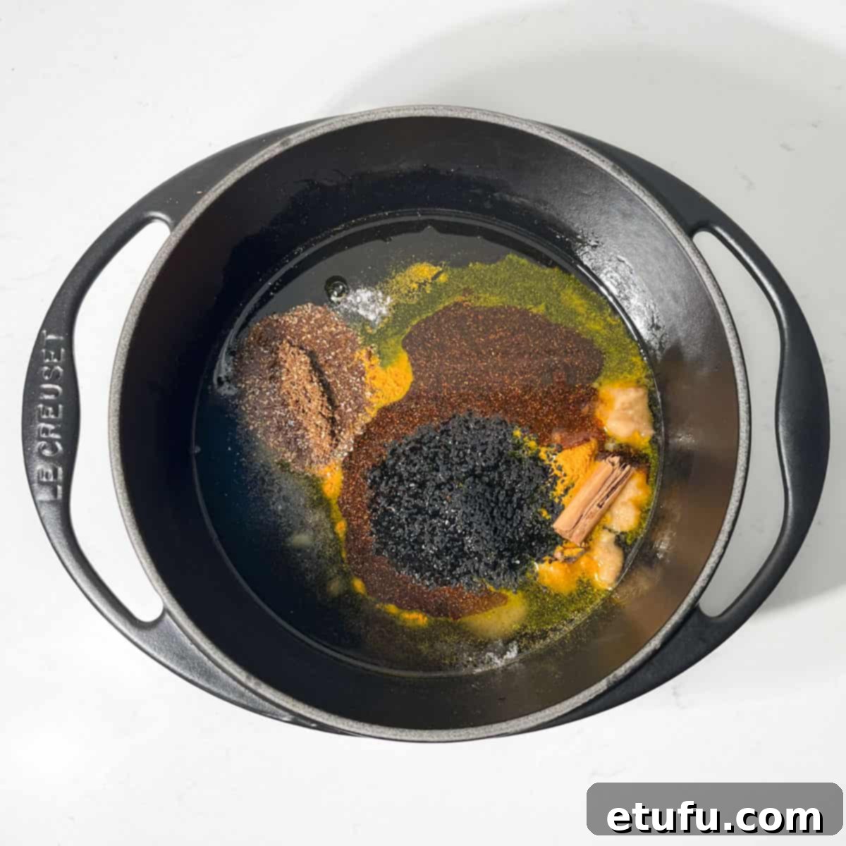 Adding all the ingredients for the mango chutney to the sugar and vinegar in a cast iron saucepan.