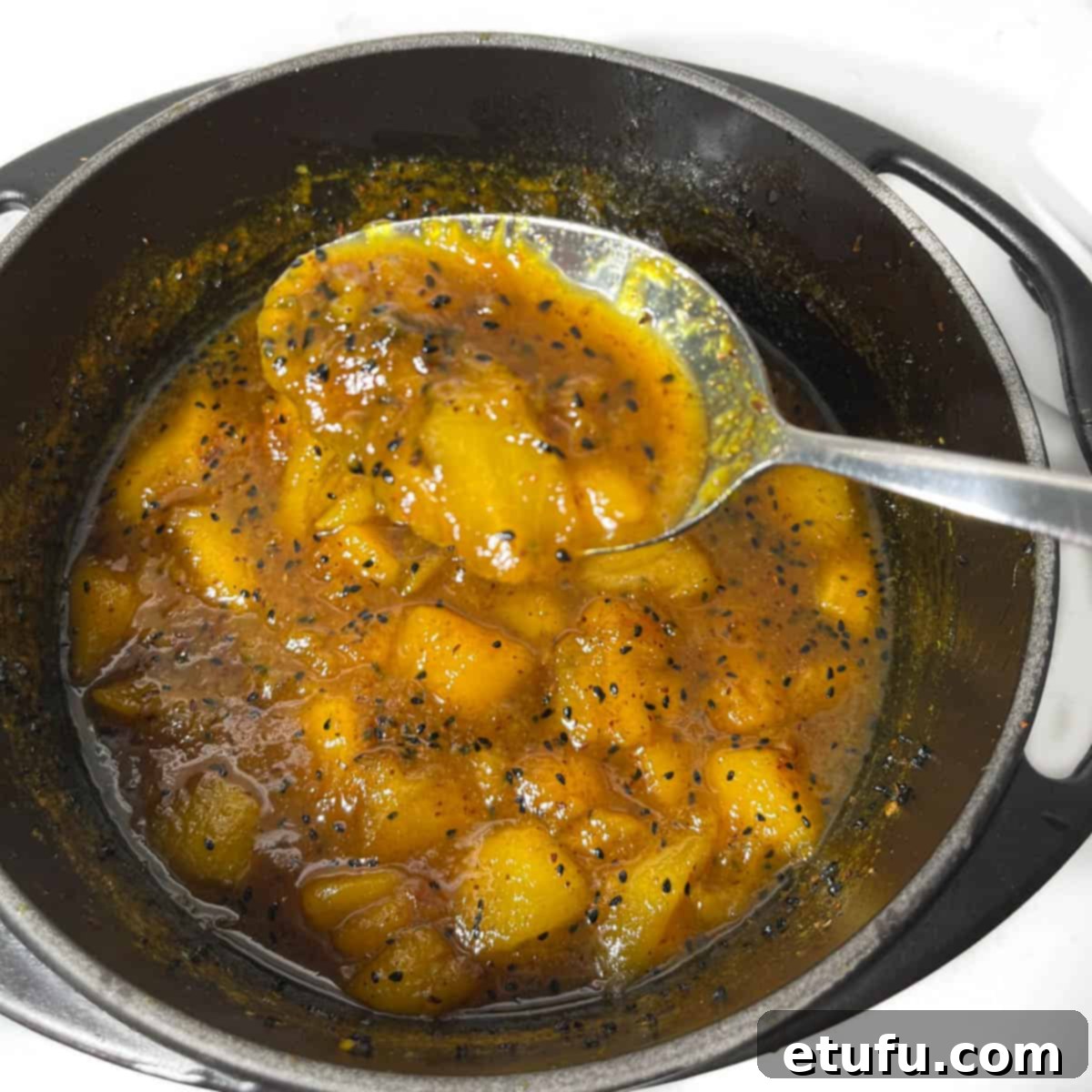 Cooked Indian mango chutney in a black cast iron saucepan.