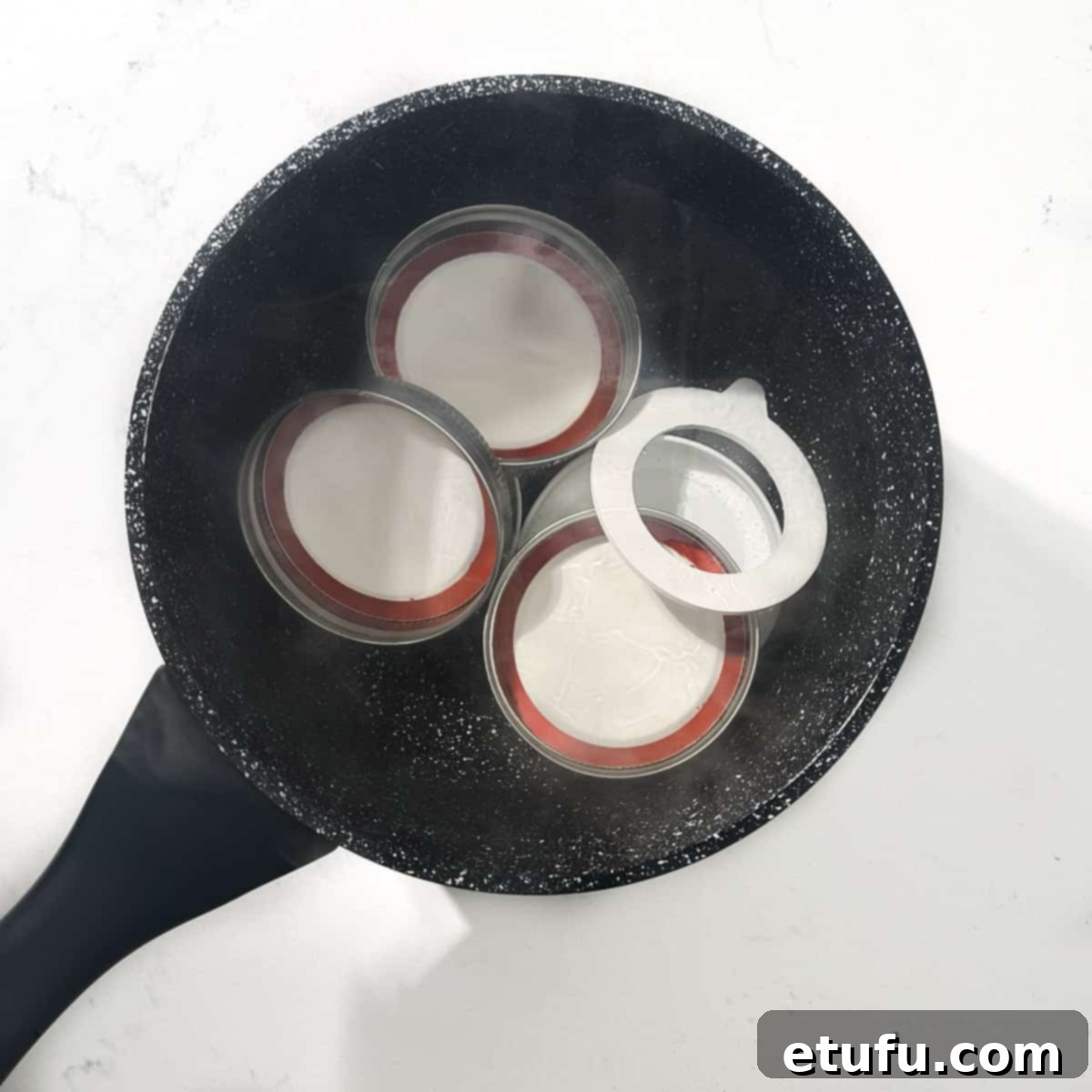 Bottle caps boiling in water in a small saucepan.