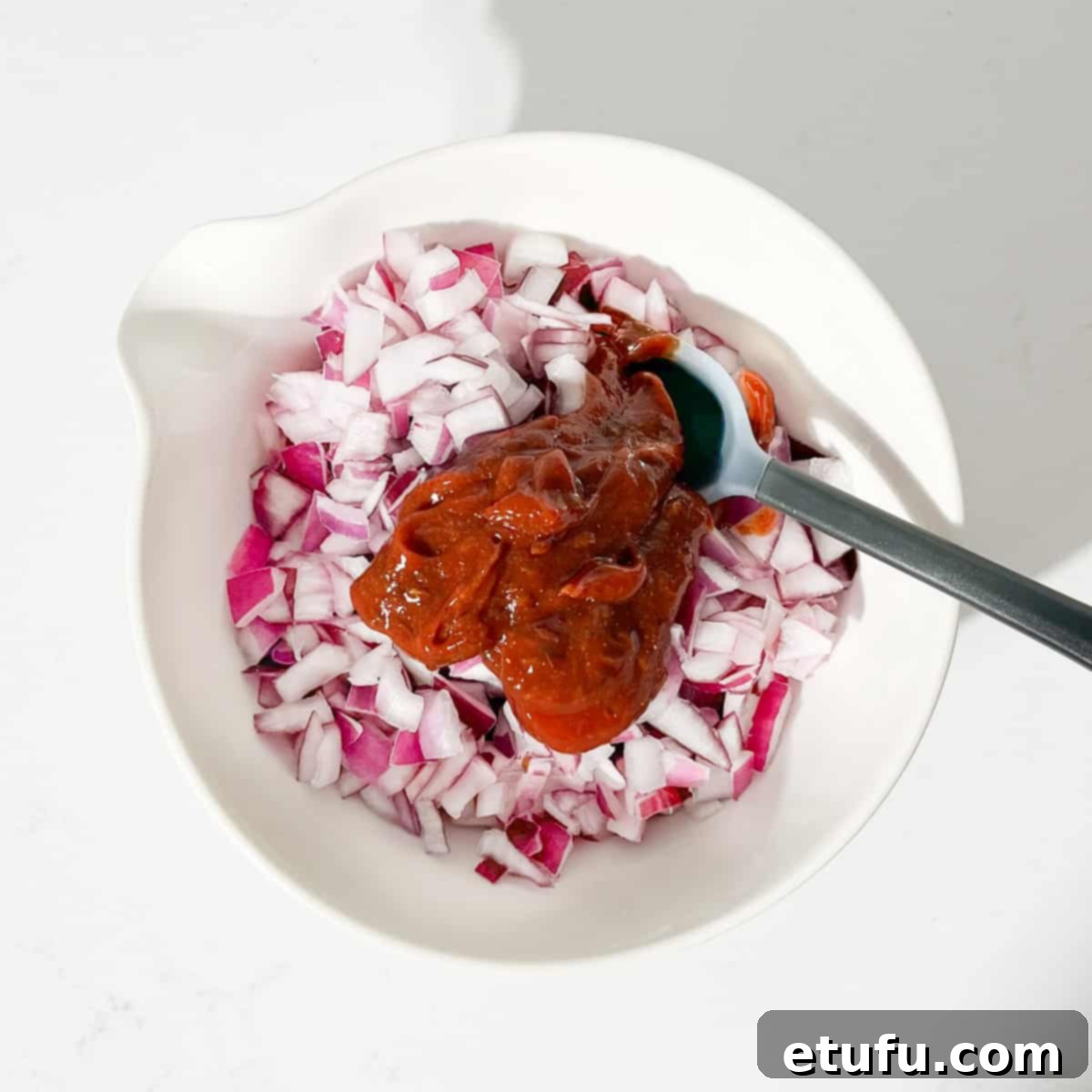Poppadom Perfection: Indian Onion Chutney 10 Adding the sauce to the chopped onions in a large white bowl.