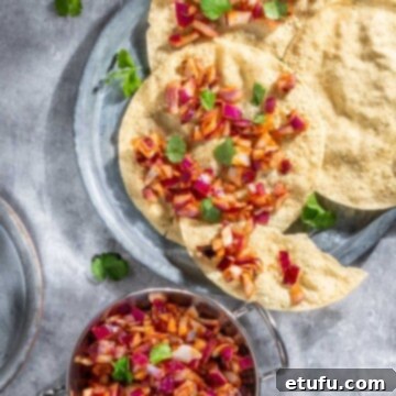 Poppadom Dip Delights 6 Bright reddish-pink Indian onion chutney spread liberally over a crispy poppadom on a grey background.
