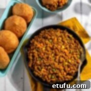 Curried mince in a black cast iron pan with a baking tin full of vetkoek.