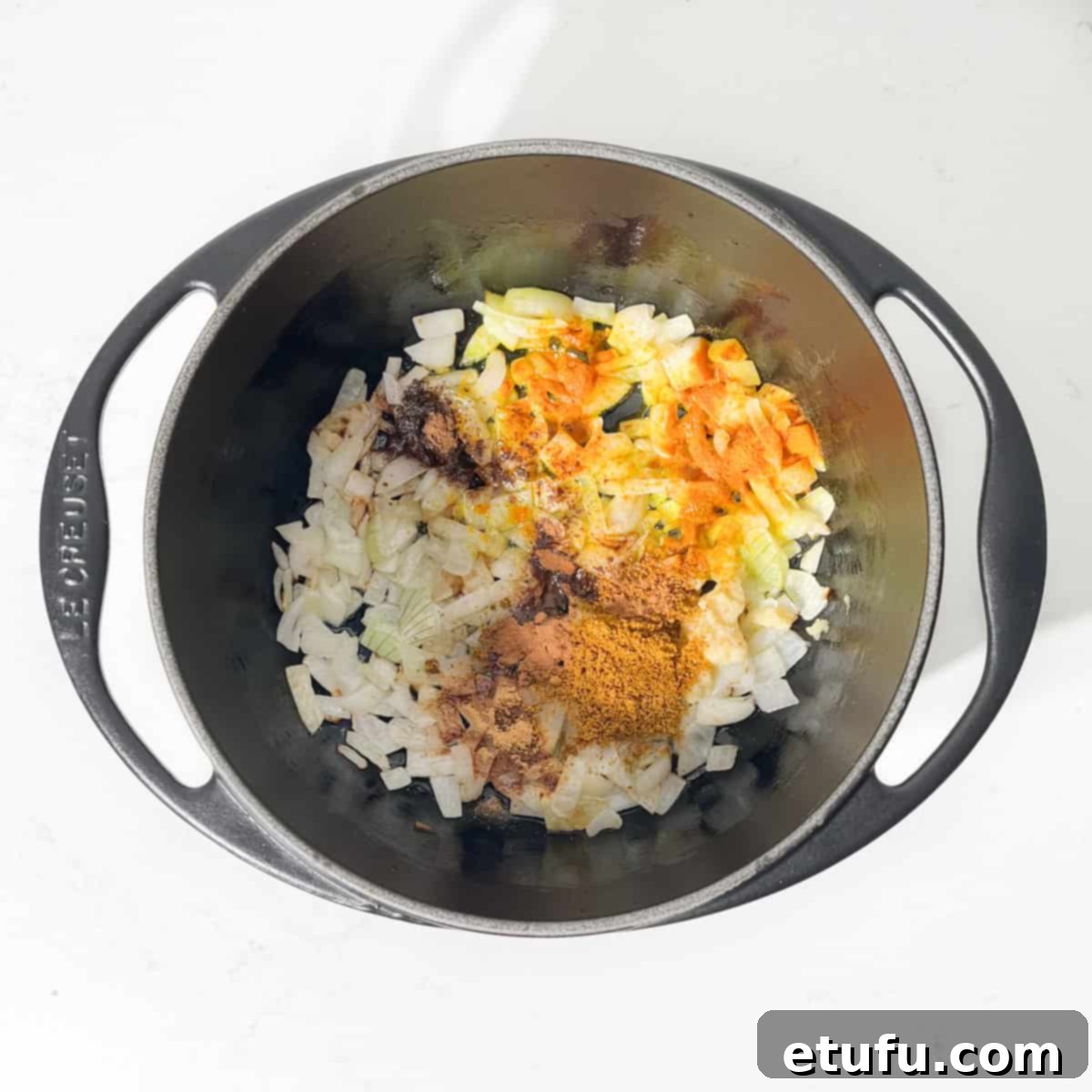 Adding all the spices to the fried onions in a saucepan for the curried mince.