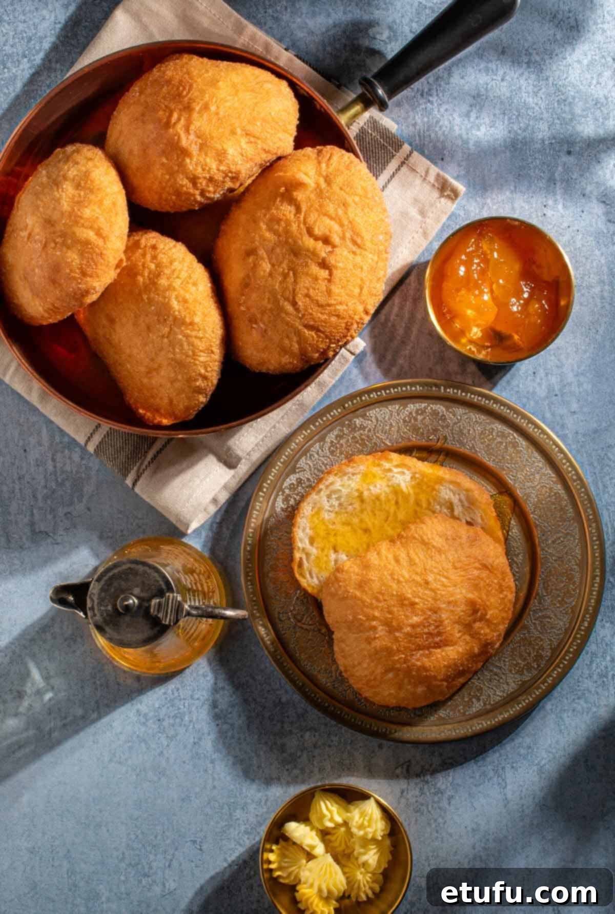 A bowl of vetkoek next to a plate with one vetkoek, drizzled in golden syrup.