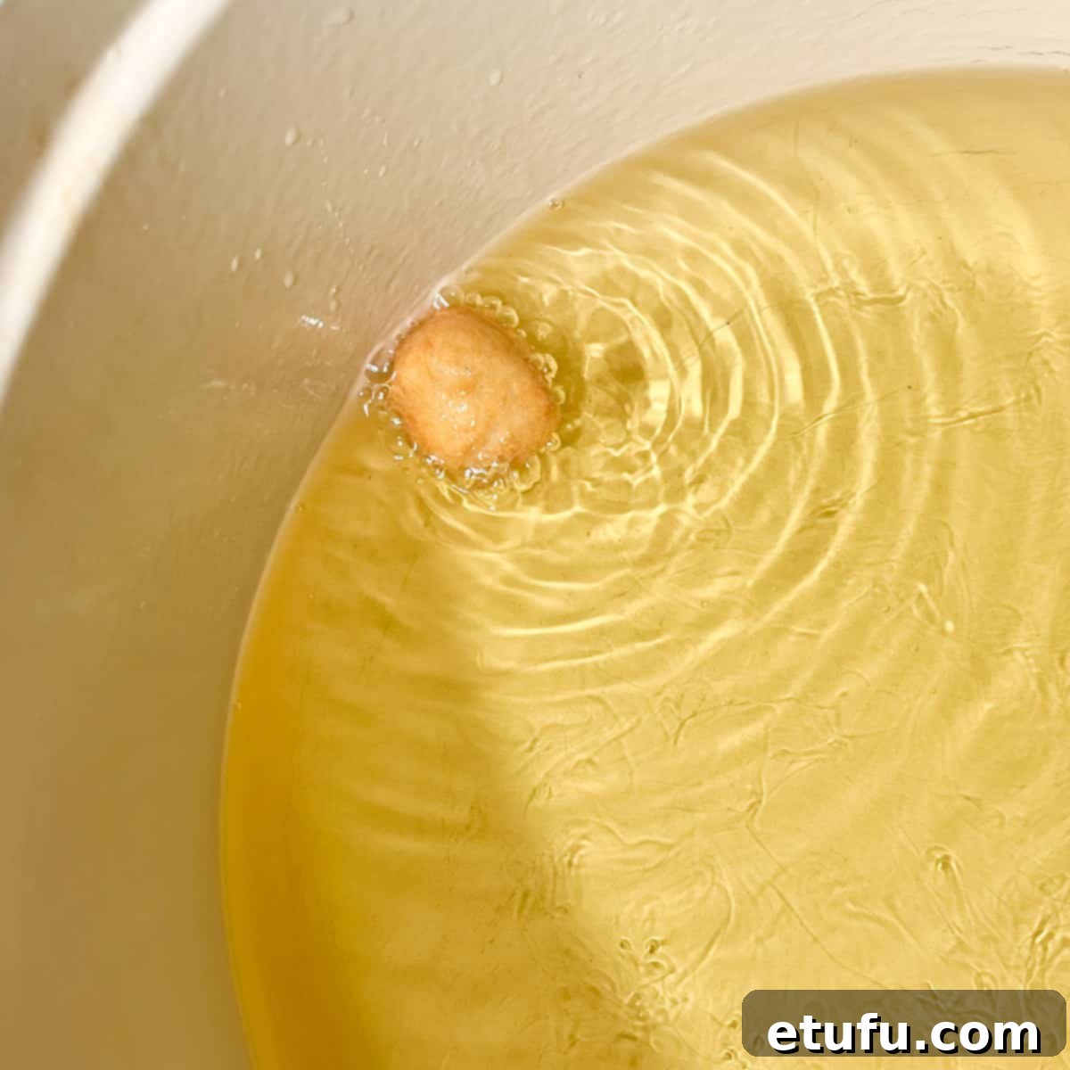 Testing the heat of the oil with a small piece of dough frying in hot oil.