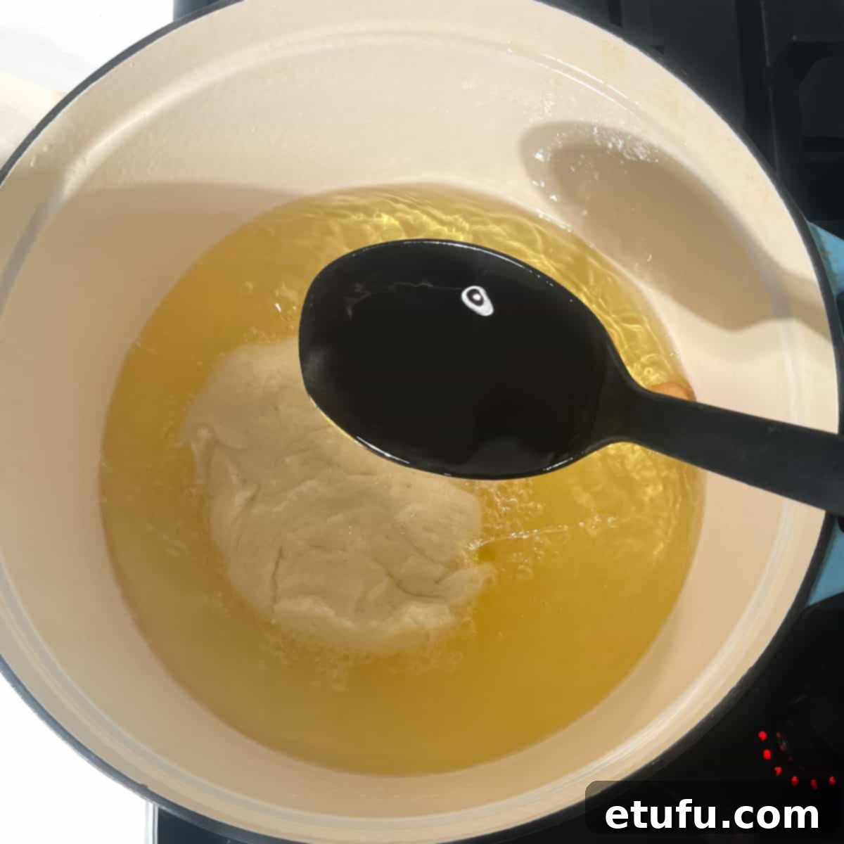 Spooning hot oil on top of a frying vetkoek.