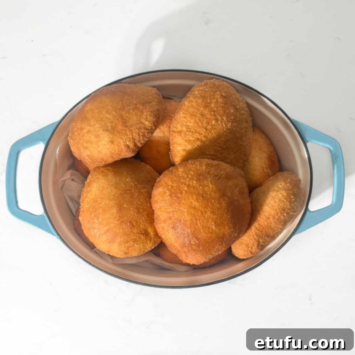 Cooked vetkoek in a large oval pot.