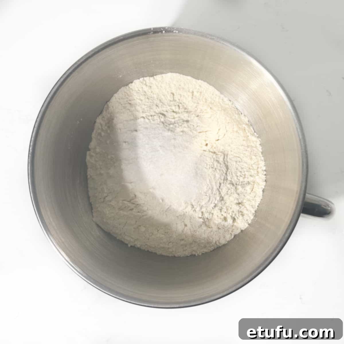 Adding salt and sugar to flour in a large mixing bowl.