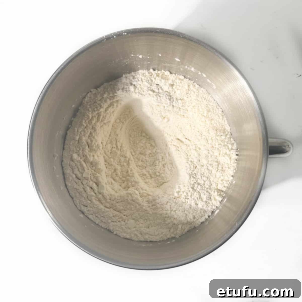 Flour in a mixing bowl with a well in the centre.