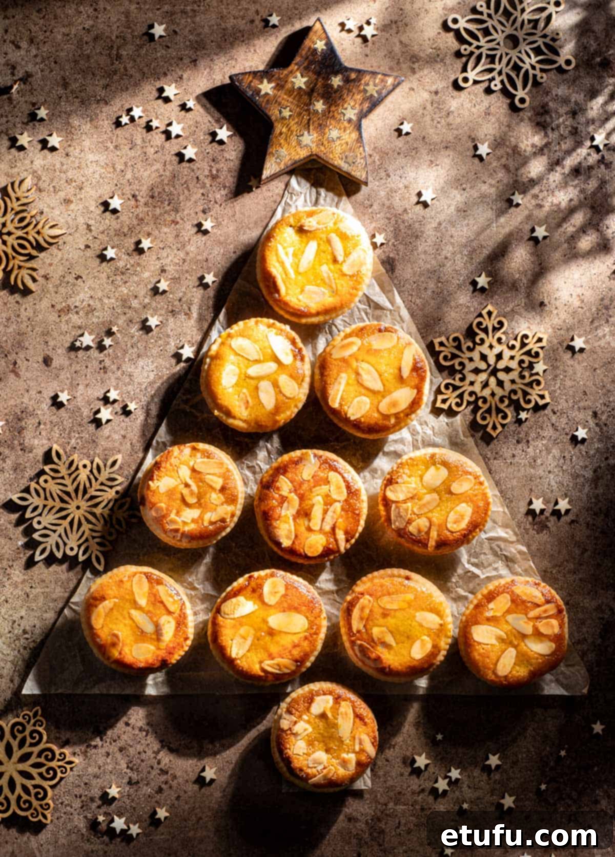 Frangipane mince pies packed in a Christmas tree shape on a brown background, ready to be enjoyed.