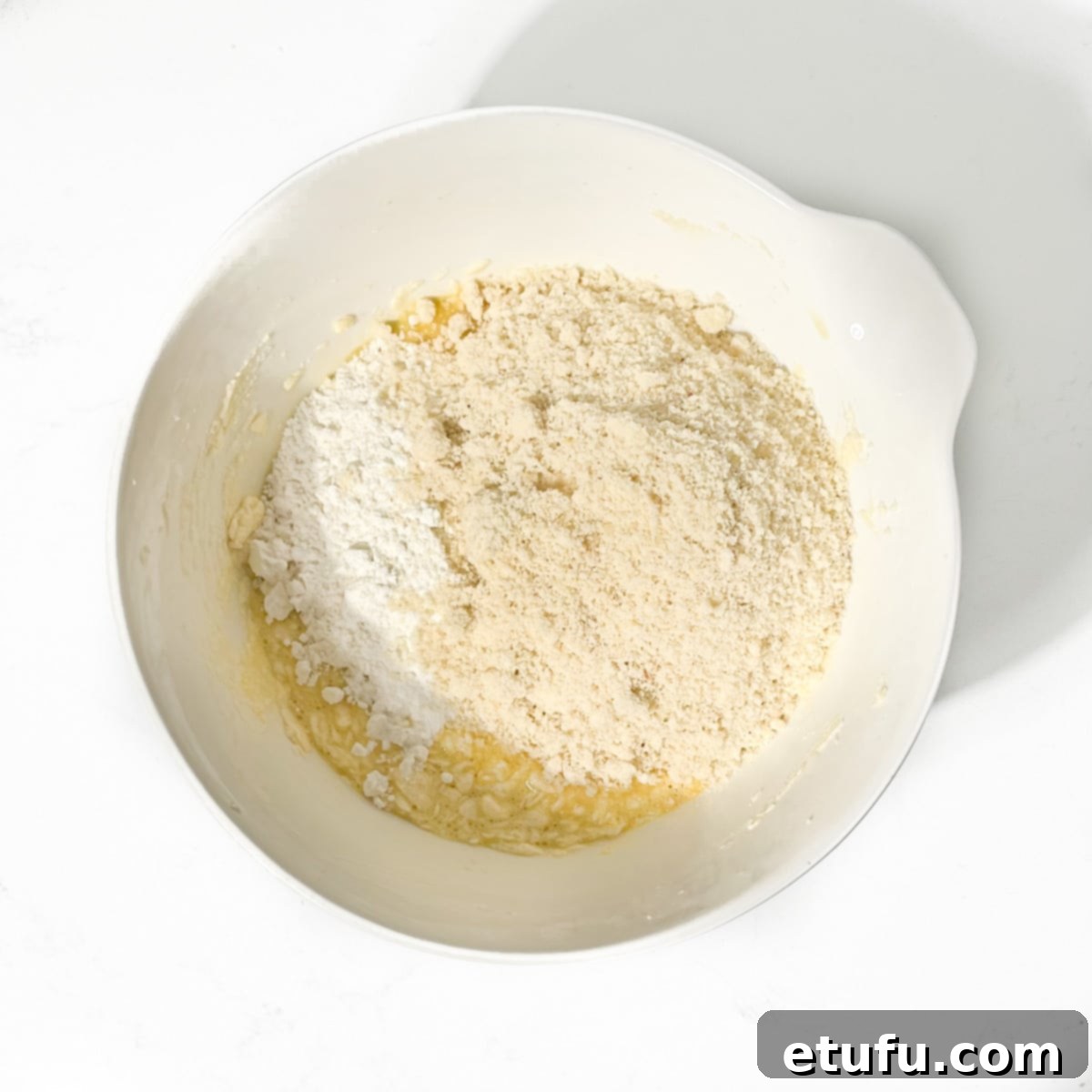 Adding ground almonds, flour, salt, and almond extract to the frangipane mixture.