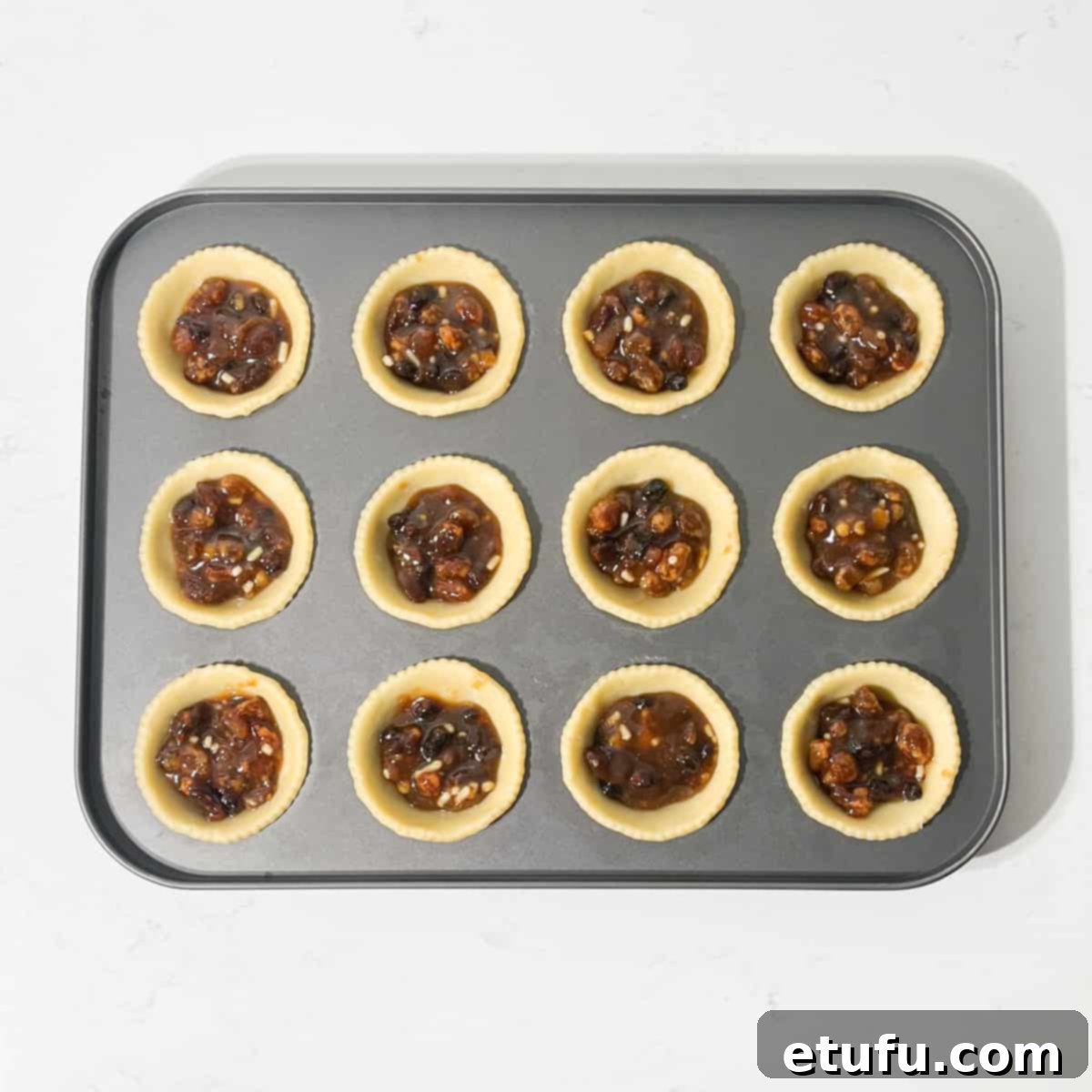 Pastry cases filled with rich mincemeat, ready for the frangipane topping.