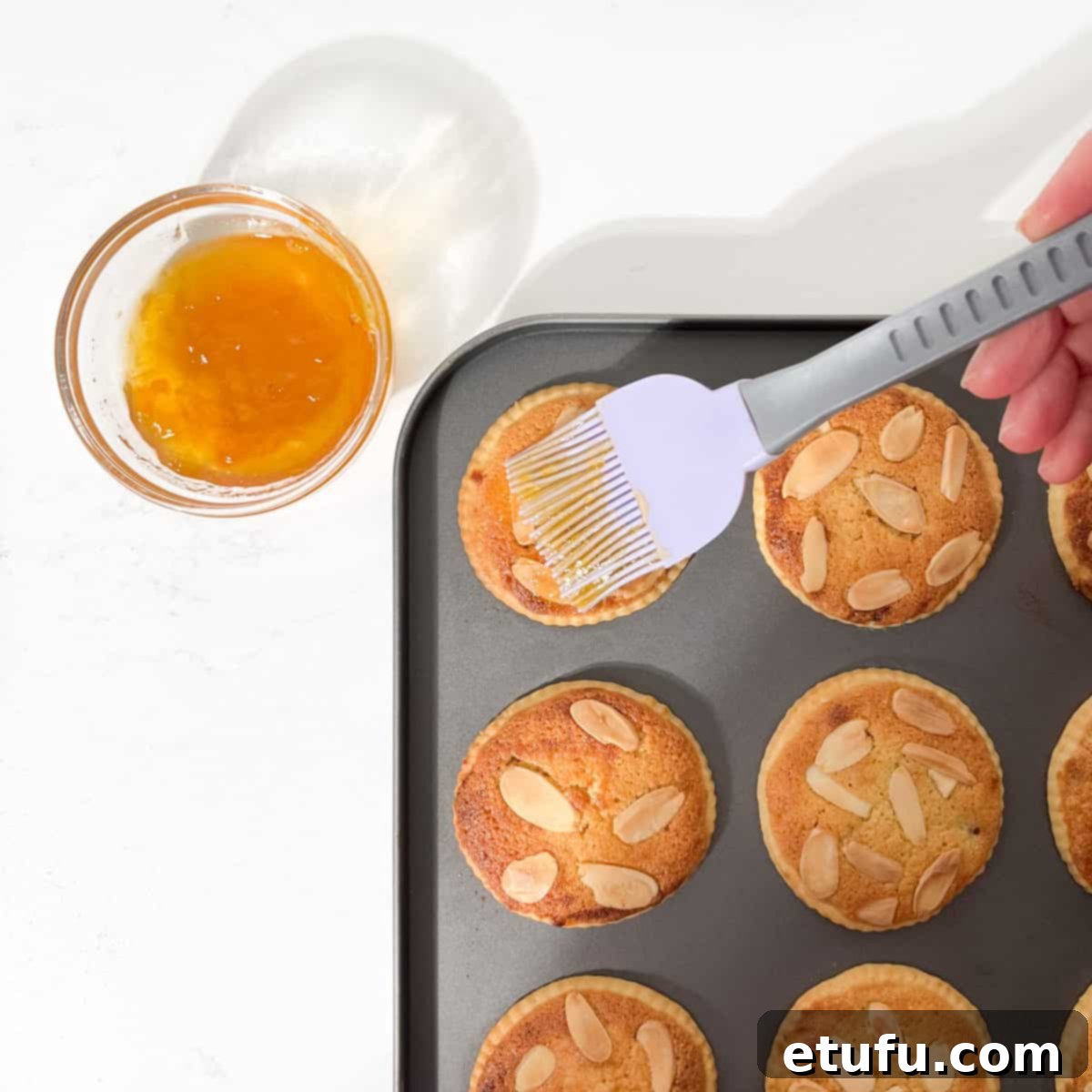 Brushing the warm frangipane mince pies with a glossy apricot jam glaze.