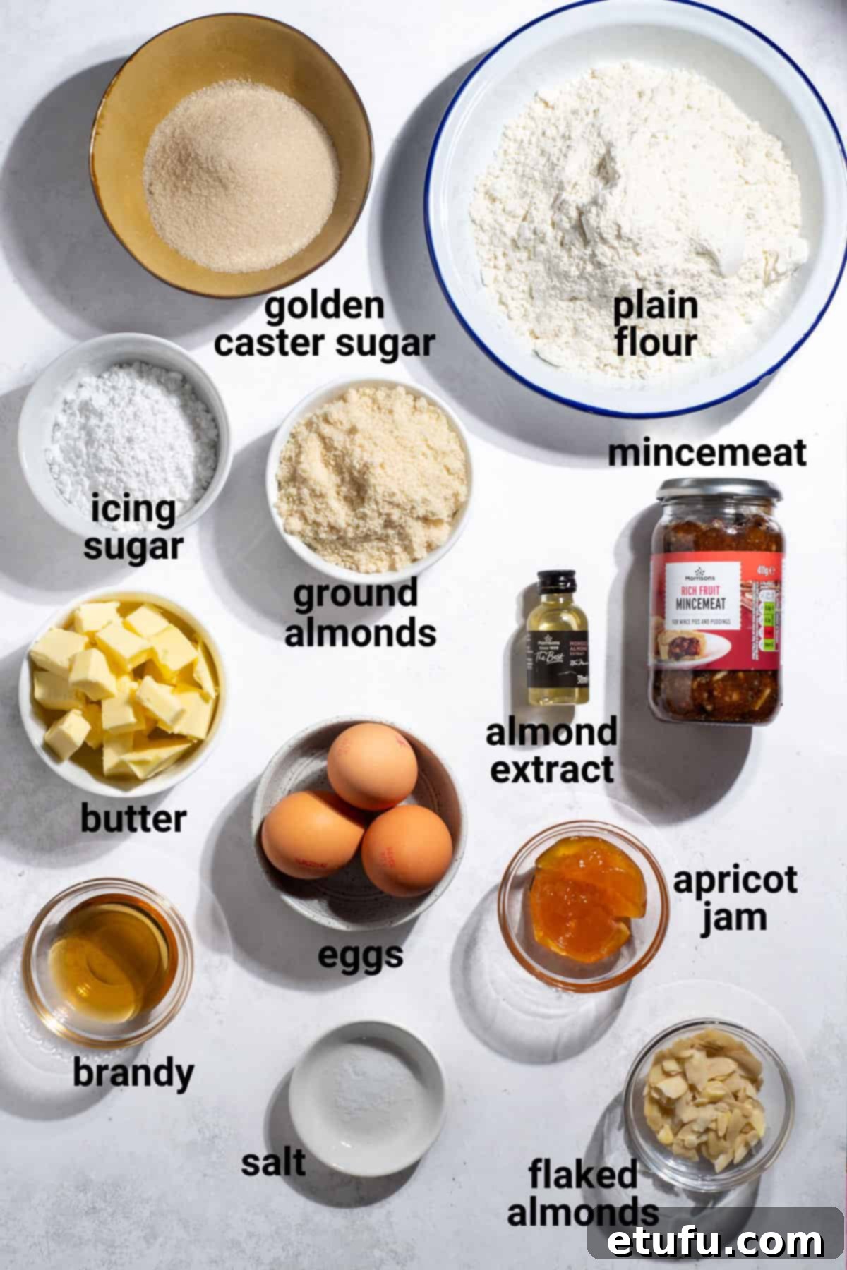 A selection of fresh ingredients laid out for making frangipane mince pies, including butter, sugar, flour, and almonds.
