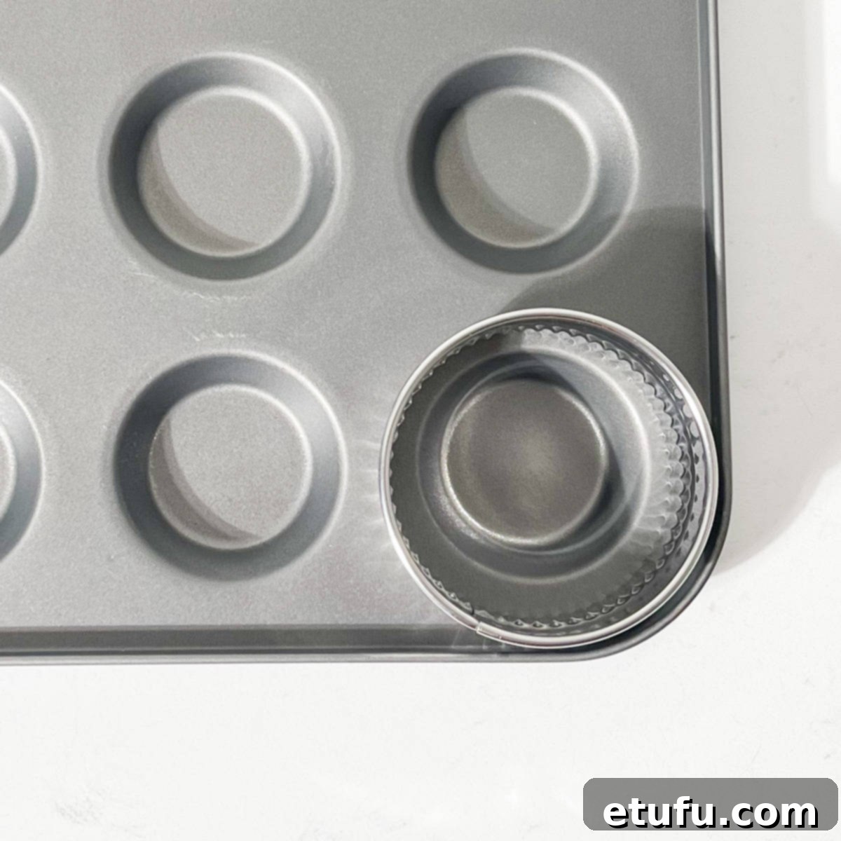 A round pastry cutter demonstrated against a fairy cake tin to show the ideal size for mince pie bases.