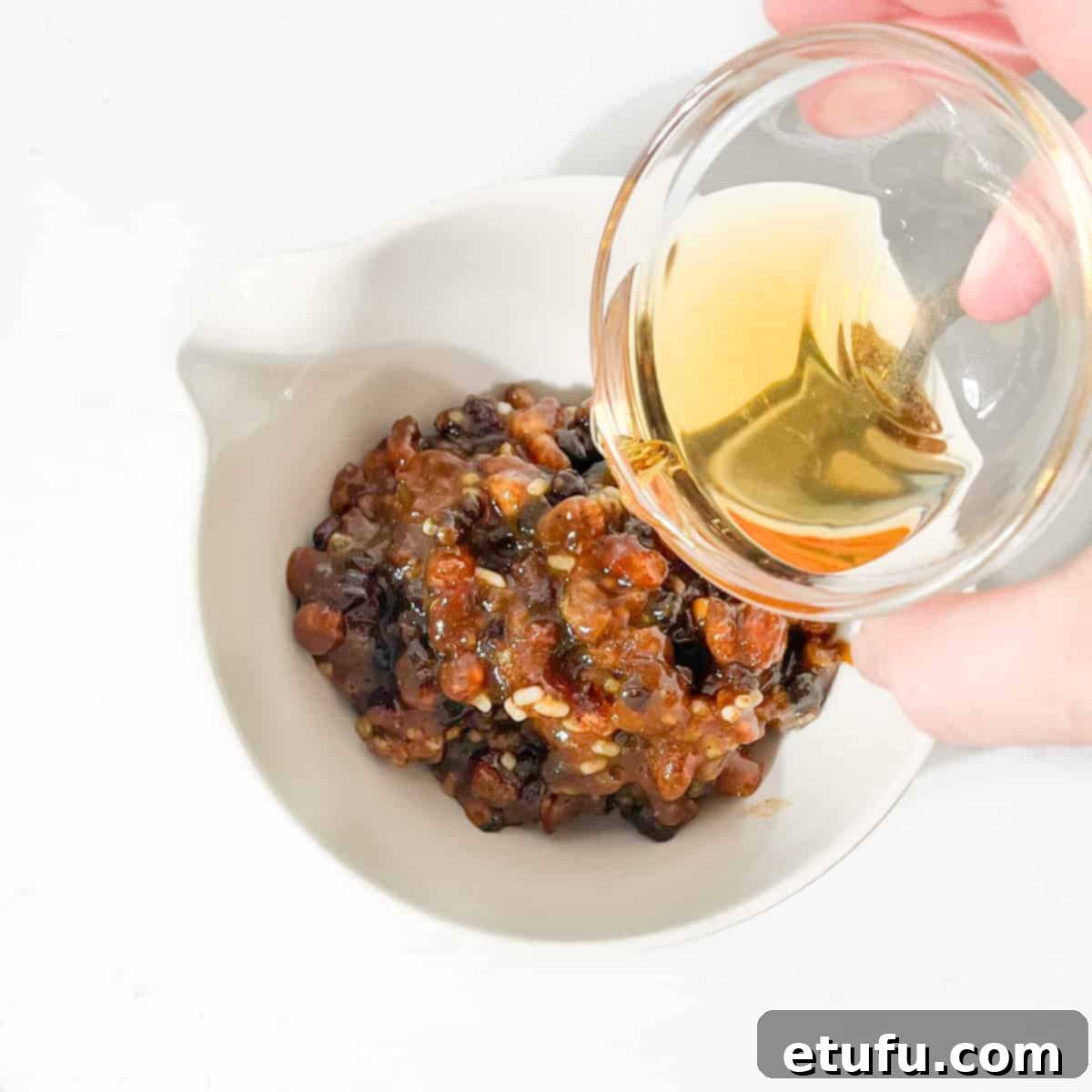 Pouring brandy into a small bowl of mincemeat, ready for mixing.