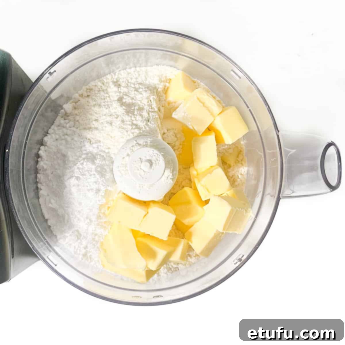 Flour and cold butter cubes added to a food processor, ready to be blended for pastry.