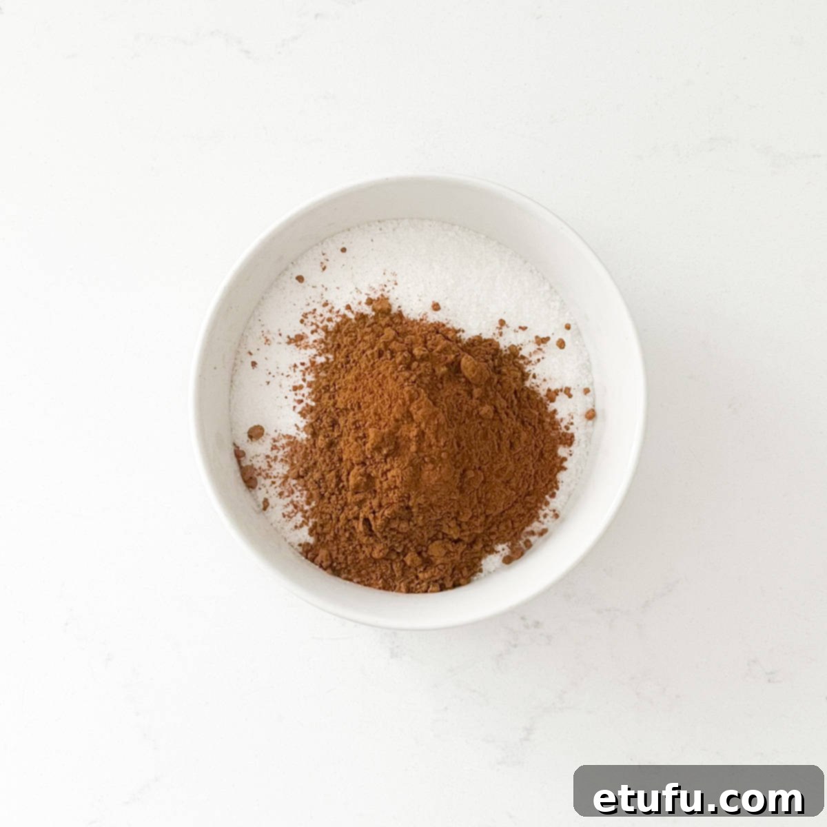 Sugar and ground cinnamon perfectly mixed in a small bowl, ready to become the delicious topping for Melkkos.