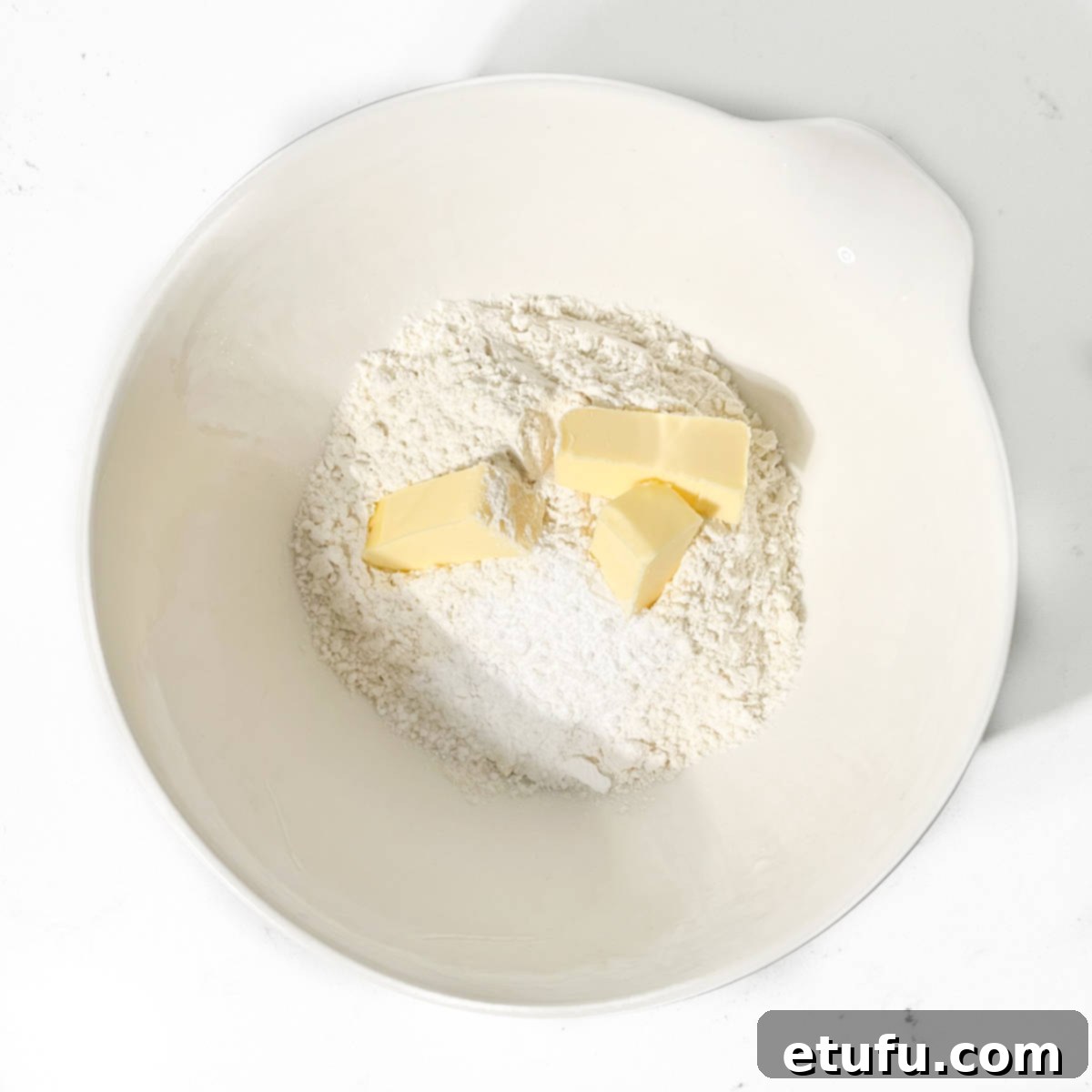 All-purpose flour, salt, baking powder, and cold, cubed butter in a white bowl, poised for the 'frummels' method of Melkkos.