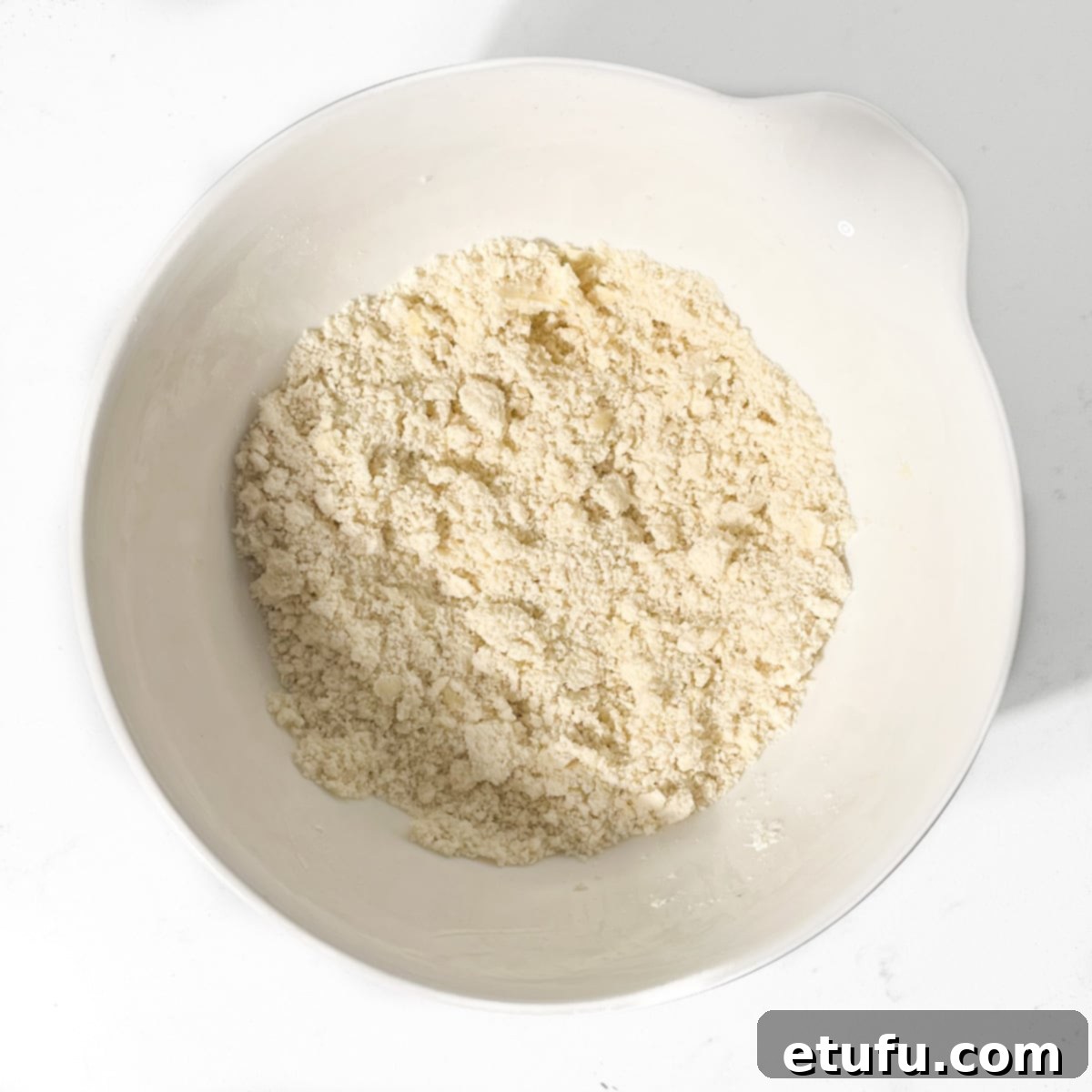 Fingertips expertly rubbing cold butter into dry ingredients, creating the coarse, breadcrumb-like 'frummels' for traditional Melkkos.