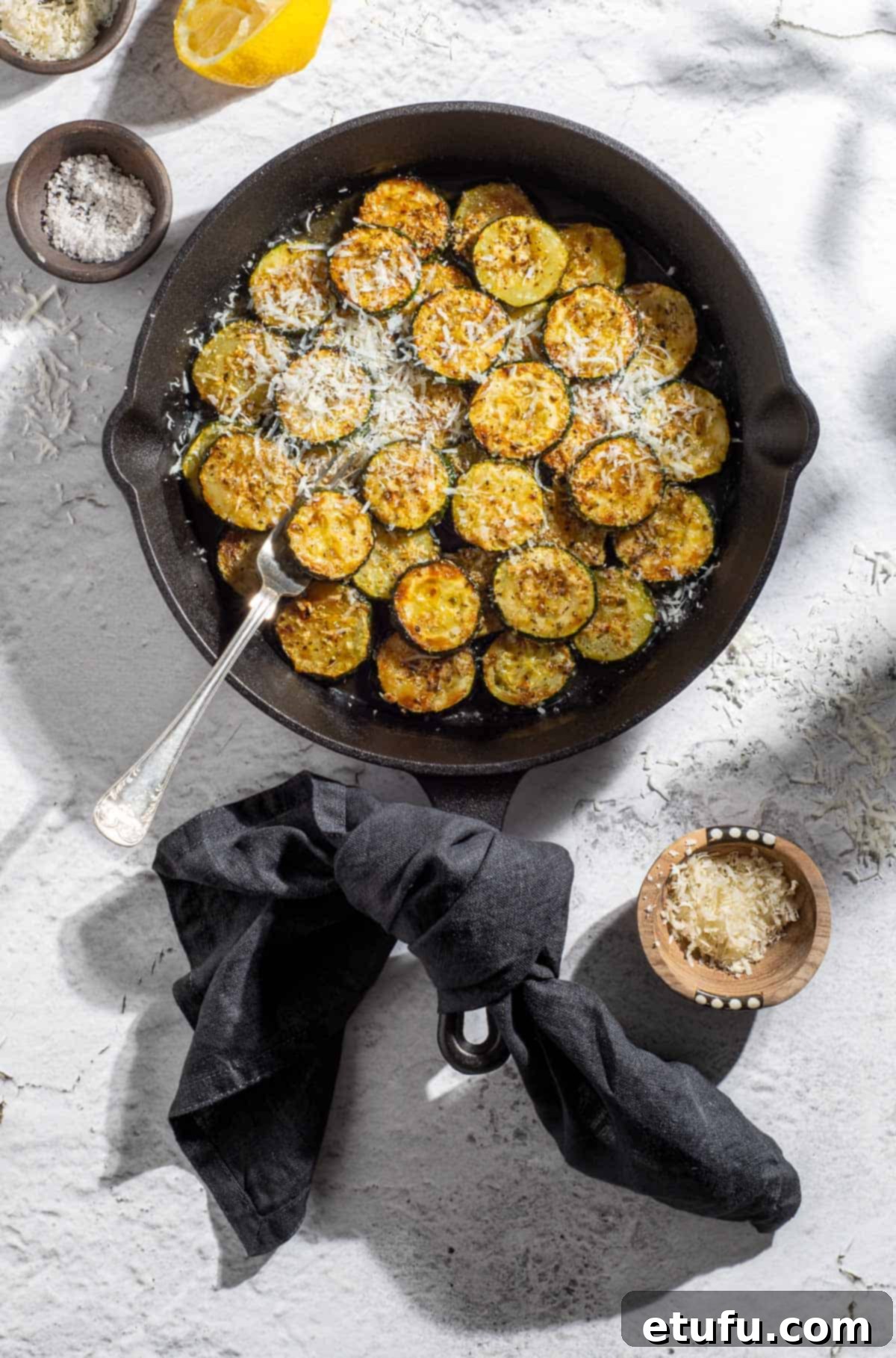 Crispy Fried Zucchini 2 Fried courgettes in a black frying pan, garnished with herbs.