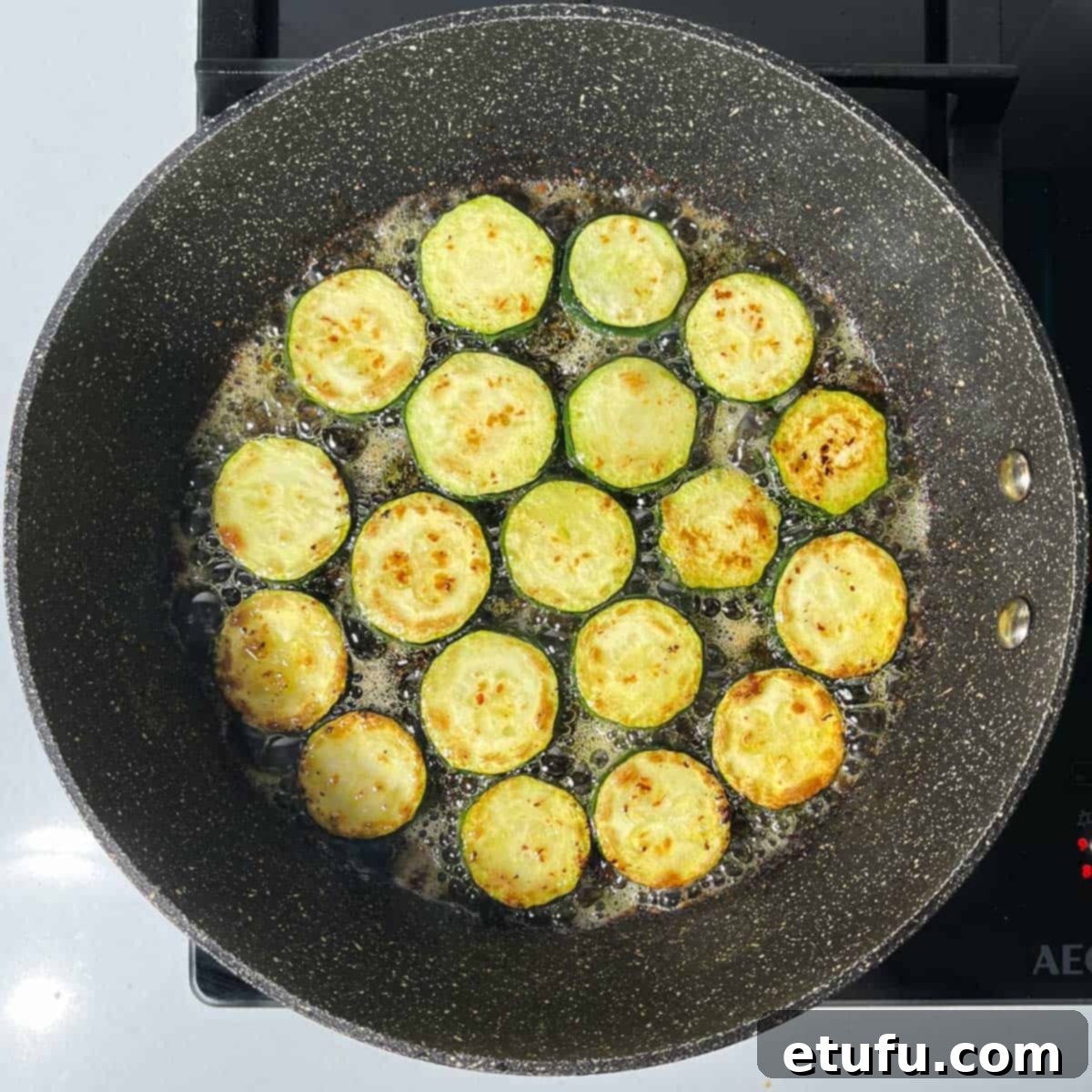 Crispy Fried Zucchini 9 Fried courgettes in a pan, with some slices turned over.