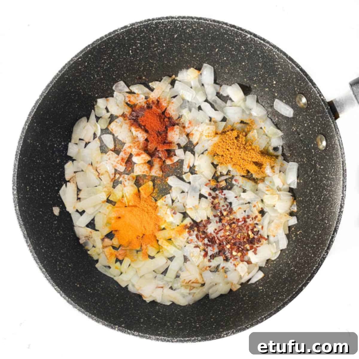 Fried onions with spices added in a frying pan.