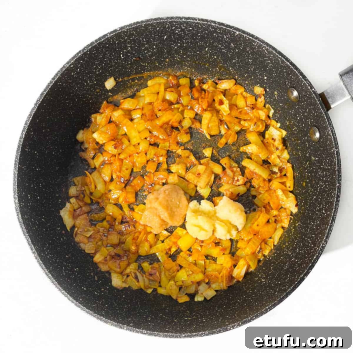 Spicy onions in a frying pan with garlic and ginger added.