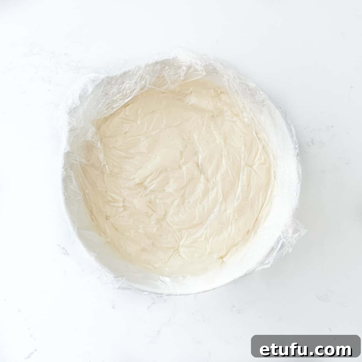 Covering the Crème Pâtissière with plastic wrap to prevent a skin from forming.