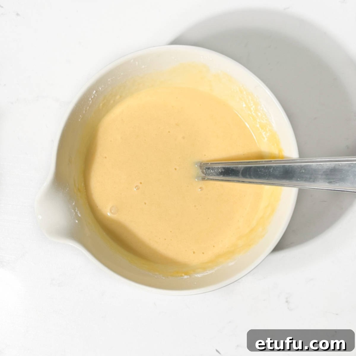Eggs, sugar and flours mixed in a small white bowl .