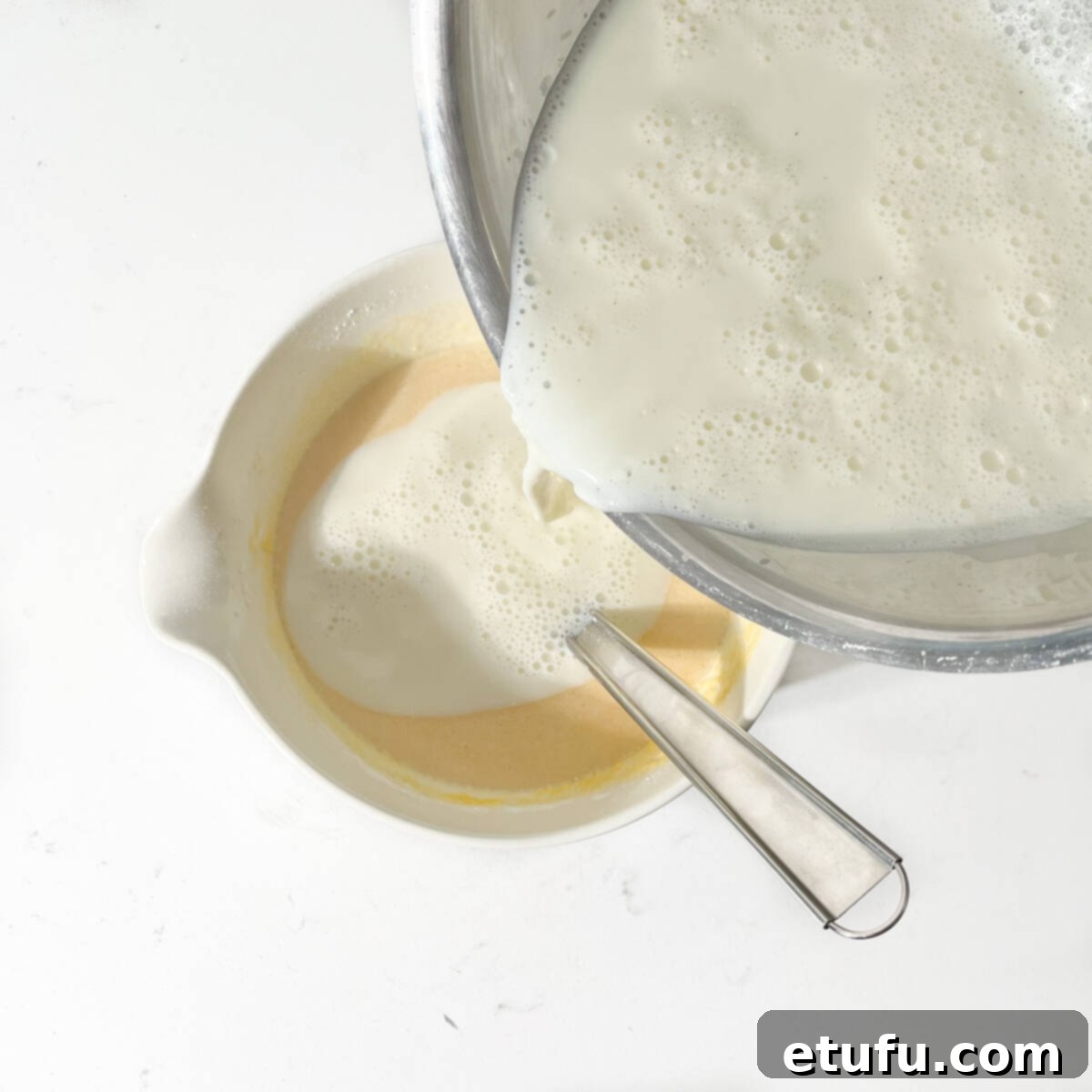 Adding hot milk to the egg and sugar mixture.