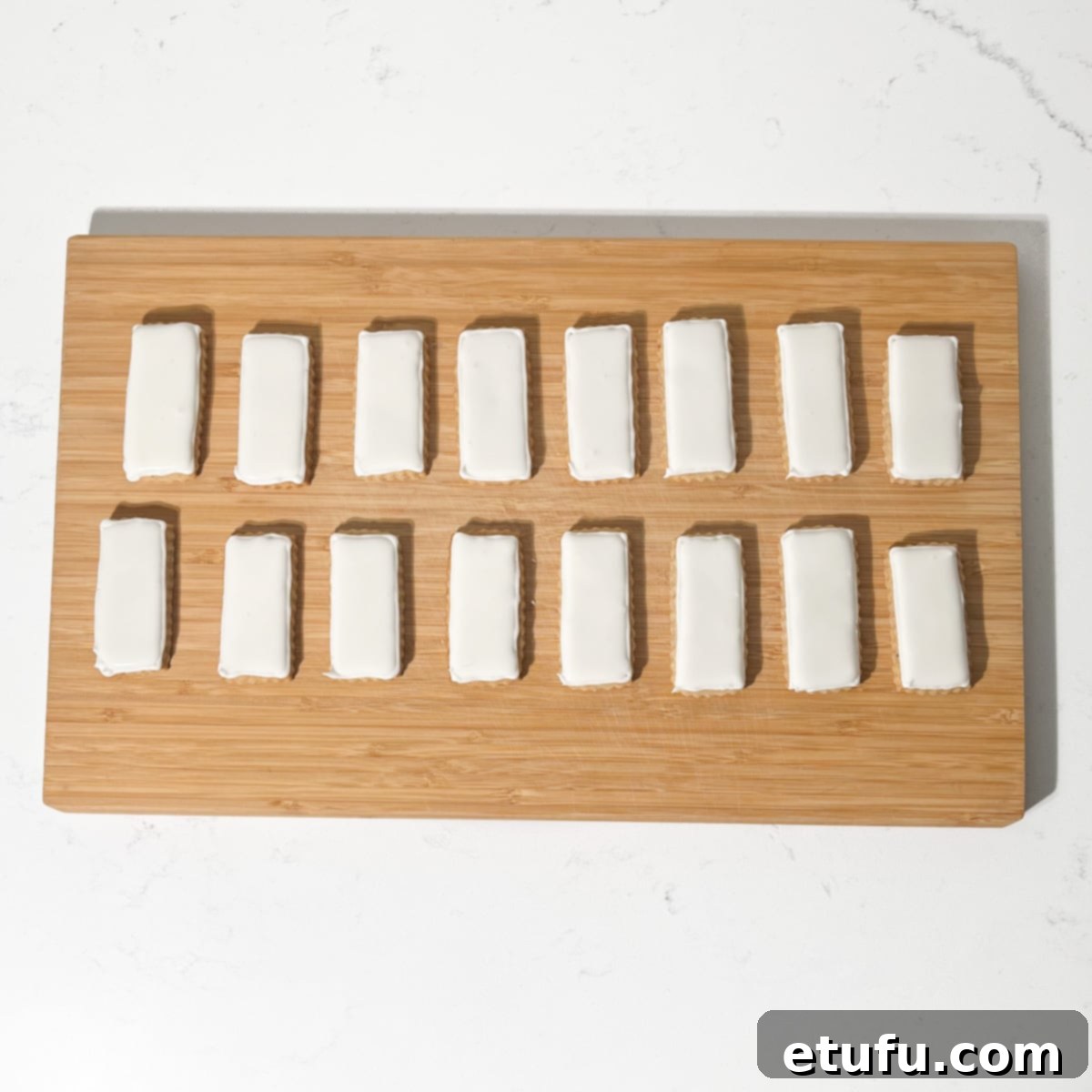 Cookies covered in white royal icing, drying on a baking rack.