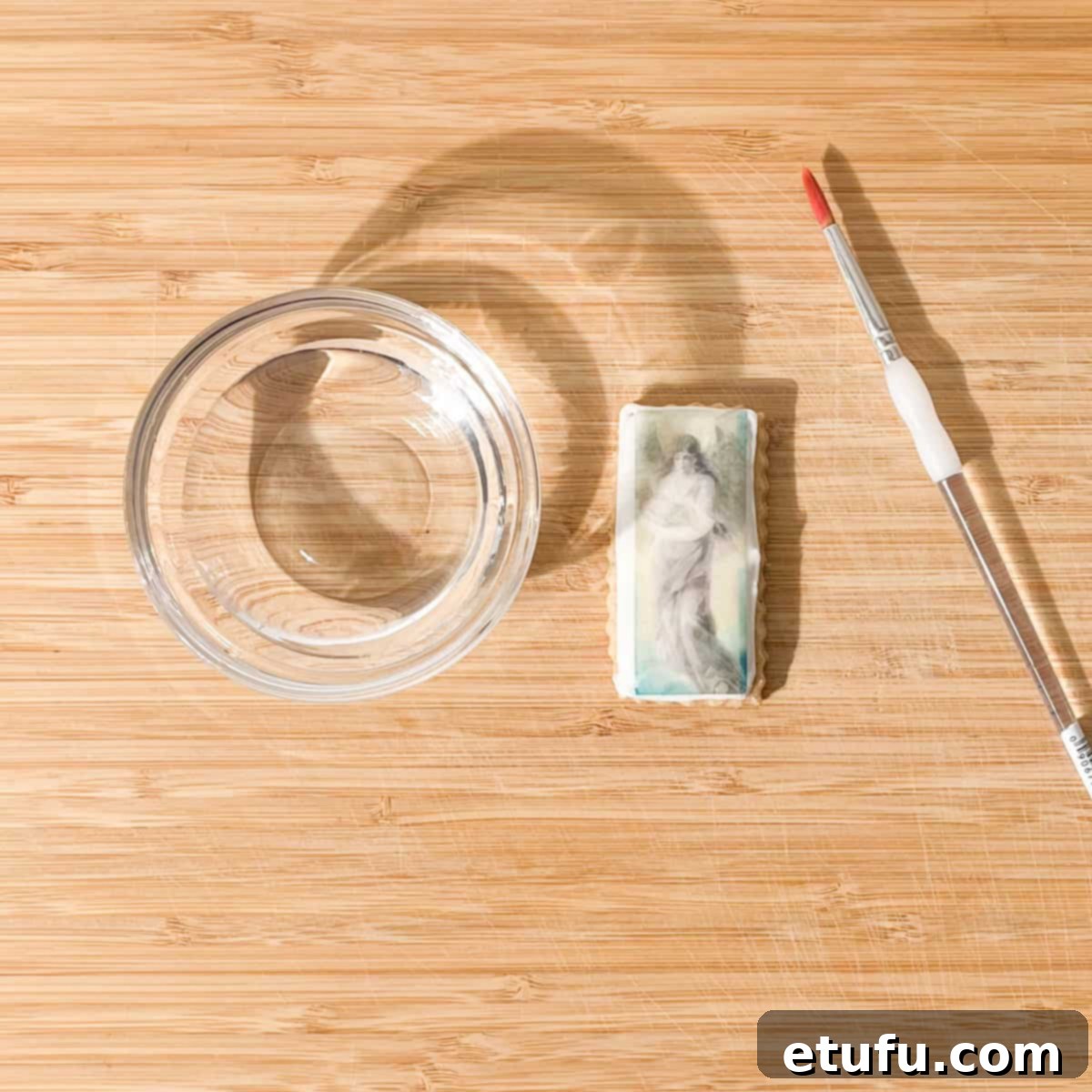 Attaching the wafer paper picture to the wet cookie, carefully pressing it into place.